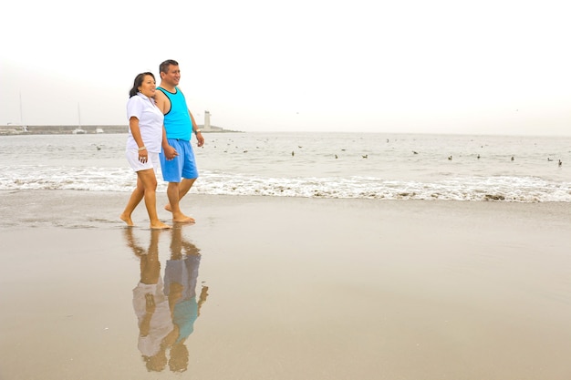 Un homme et une femme mûrs de 50 ans marchent sur une plage heureux et amoureux