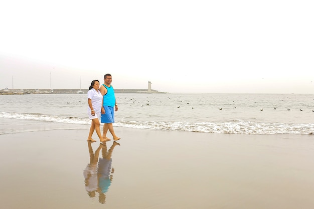 Un homme et une femme mûrs de 50 ans marchent sur une plage heureux et amoureux