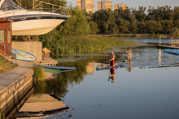 Homme et femme sur des planches de sup sur la rivière le soir