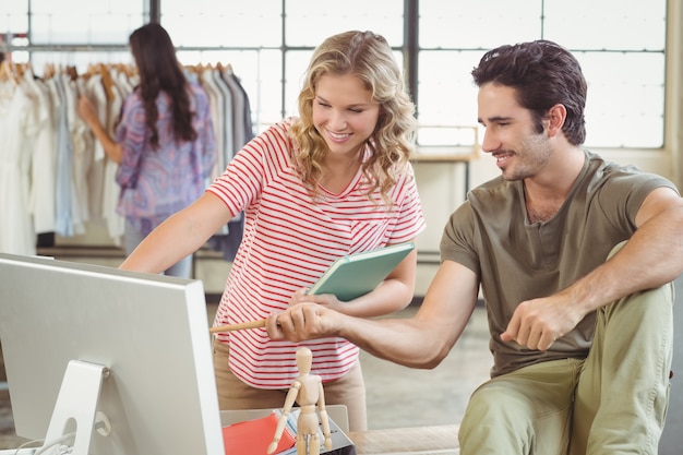 Homme et femme pointant vers l&#39;ordinateur au bureau