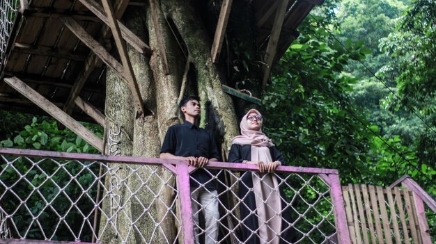 Photo un homme et une femme sur un pont contre des arbres dans la forêt