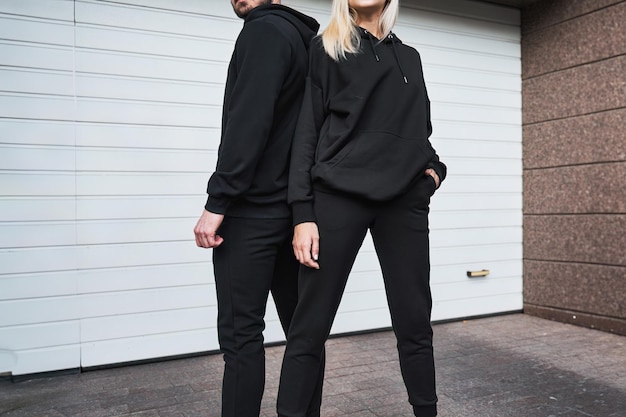 Homme et femme portent des capuchons noirs Un modèle de mode pour l'impression et l'image de marque sur le capuchon Un couple à la mode dans la rue portant des vêtements décontractés sans visage visible Sans pull et pull avec capuche.