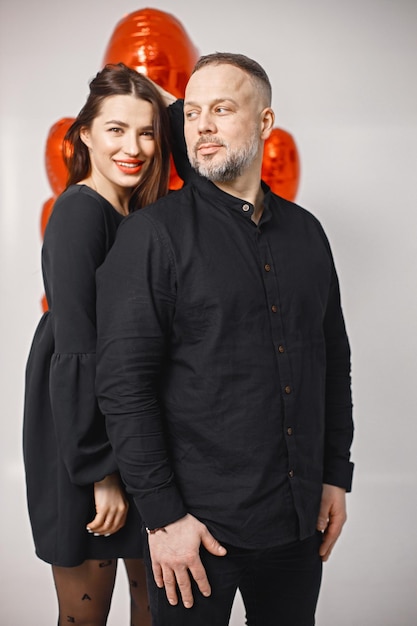 Homme et femme posant en studio près de bouquet de ballons rouges en forme de coeur