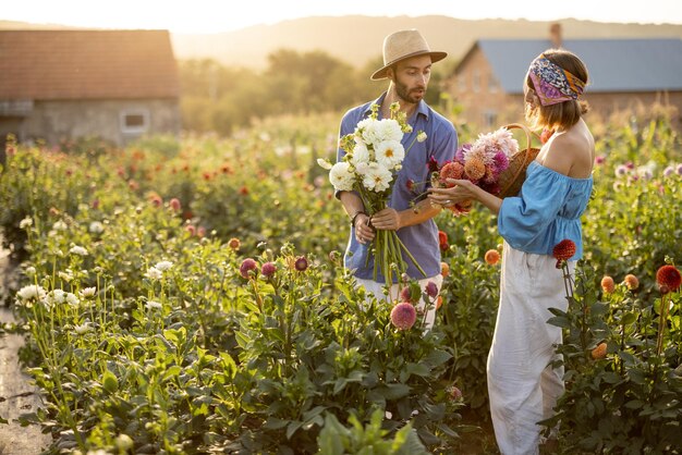 Un homme et une femme ramassent des fleurs à la ferme à l'extérieur