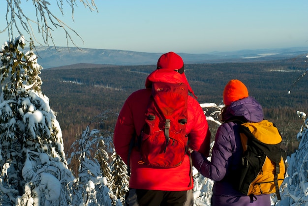 L'homme et la femme randonneurs se tiennent dos au spectateur au sommet de la montagne