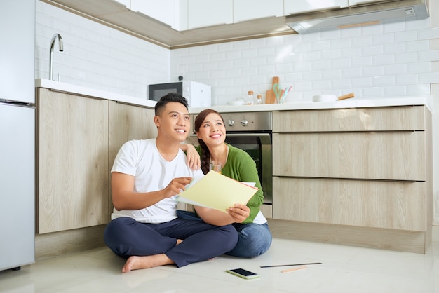 Homme et femme regardant leurs plans de maison assis dans leur nouvelle maison