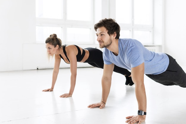 Homme et femme de remise en forme pendant l'entraînement avec dans la salle de gym. Exercice de pompes pour les muscles de la poitrine et des triceps.