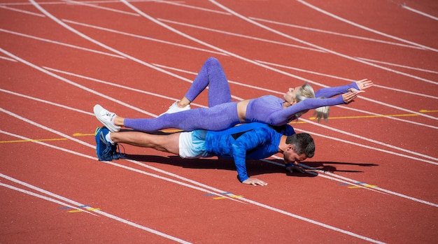 L'homme et la femme de remise en forme sportive s'entraînant ensemble se tiennent en planche et poussent vers le haut