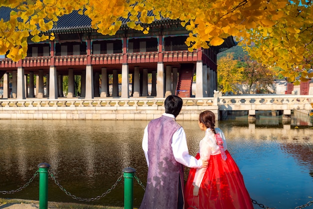 Homme et femme en robe hanbok à pied dans le palais de Séoul dans le jardin d'automne de Ginkgo