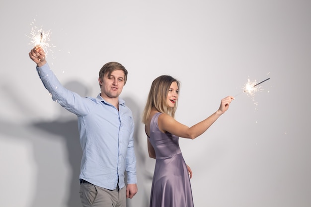 Homme et femme s'amuser avec des cierges magiques sur mur gris
