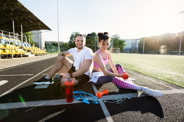 Un homme et une femme s'assoient dans le stade et rient Activités sportives de plein air