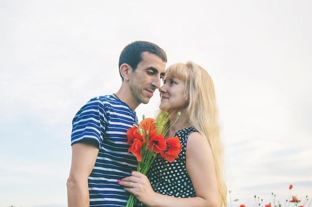 Homme et femme s'embrassent dans le champ de coquelicots selective focus