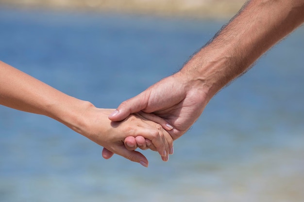 L'homme et la femme se gardent pour les mains contre l'eau de mer sur la plage en gros plan