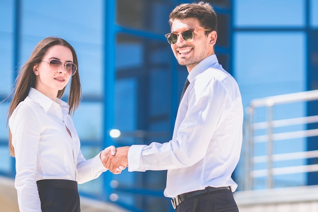 L'homme et la femme se serrent la main l'arrière-plan du centre d'affaires