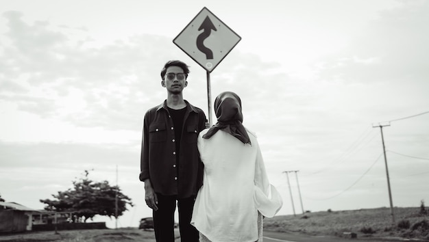 Un homme et une femme se tiennent sous un panneau de signalisation indiquant "je vais à droite"