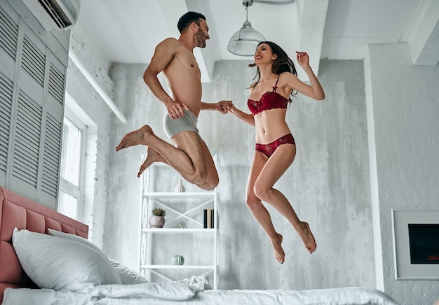 L'homme et la femme sexy en sous-vêtements sautant sur le lit