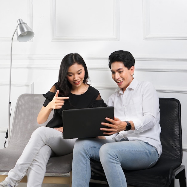 Un homme et une femme sont assis sur un canapé et regardent un ordinateur portable.