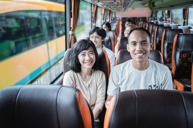 Un homme et une femme sourient assis dans le bus lors d'un voyage