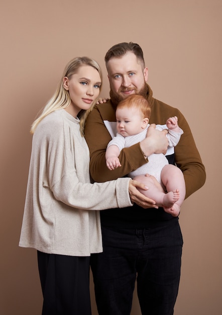 Un homme et une femme tiennent un bébé dans leurs bras.