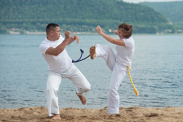 Homme et femme train capoeira sur la plage - concept sur les gens, mode de vie et sport.