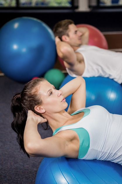 Homme et femme travaillant sur ballon de fitness