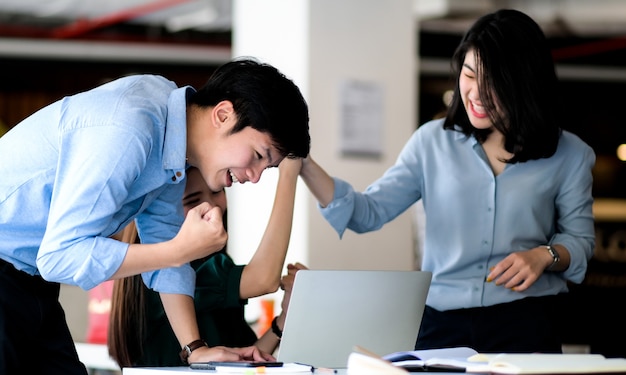 Un homme et une femme utilisent un ordinateur portable pour vérifier la bourse et montrer de la joie.