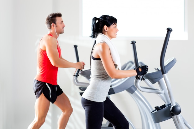 homme et femme avec vélo elliptique au gymnase