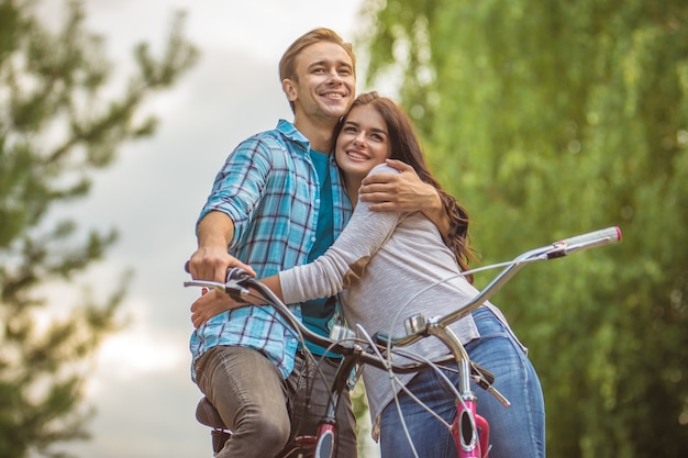 L'homme et la femme avec des vélos s'embrassent en plein air