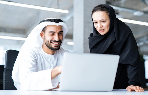 Homme et femme avec des vêtements traditionnels travaillant dans un bureau d'affaires de Dubaï