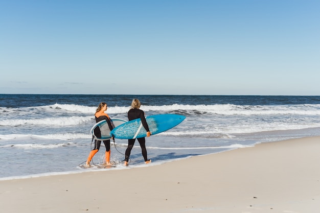 homme et femme vont à l&#39;océan avec des planches de surf. homme et fille vont surfer