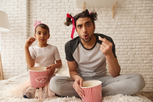 Un homme et une fille arabes mangent du pop-corn dans le lit.