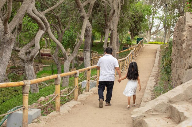 un homme et une fille marchent sur un chemin avec des arbres en arrière-plan