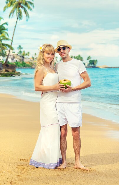 Un homme et une fille sur la plage boivent de la noix de coco