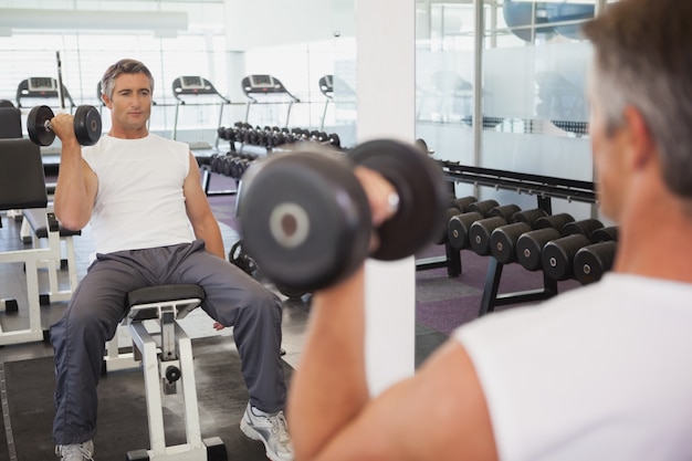 Homme fit soulever des haltères assis sur le banc