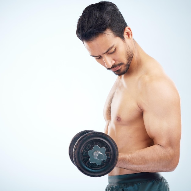 Homme fitness et haltère en studio pour le bien-être musculaire et les soins personnels sur fond bleu avec mise au point