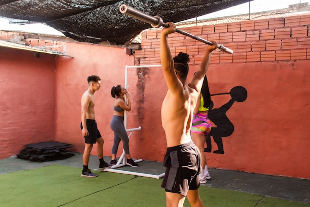 Un homme de fitness s'arrache pendant que ses copains se reposent sur l'aire de jeux de la salle de sport.