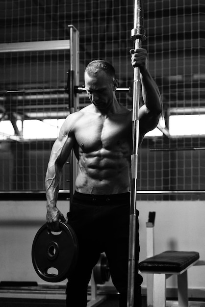 Homme fléchissant les muscles avec des haltères et des poids