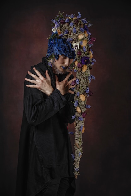 Un homme avec des fleurs bleues sur une pièce sombre