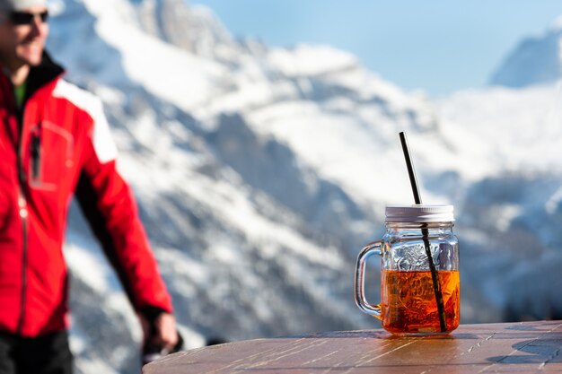 Un homme sur le fond des montagnes va à la table sur laquelle il y a une tasse d&#39;aperol.