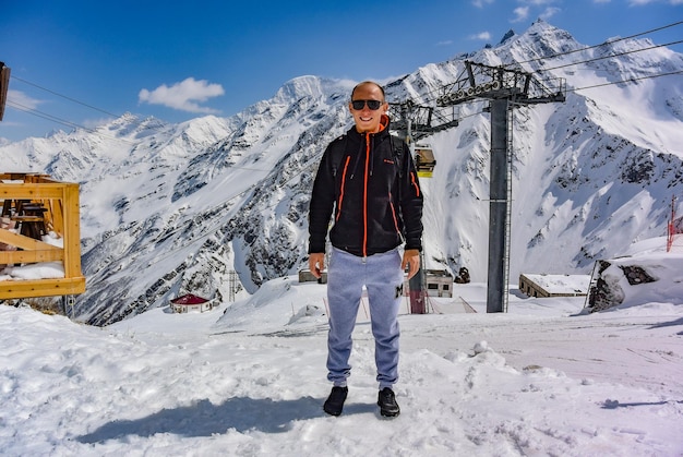 Photo un homme sur le fond d'un téléphérique de gondole et les montagnes enneigées d'elbrus 2019 russie