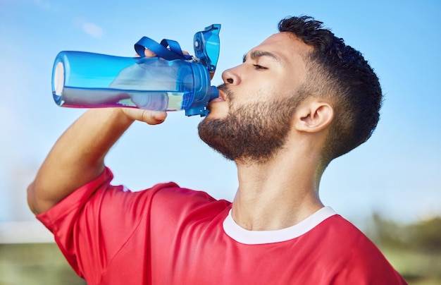 Homme football et hydratation eau potable pour la santé sportive et l'énergie dans le fitness à l'extérieur Joueur de football athlétique avec boisson pour rafraîchir la soif et la durabilité de l'entraînement ou de l'exercice sportif
