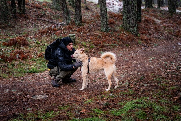 L'homme de la forêt d'hiver et le chien de compagnie partagent un lien au milieu des grands pins.