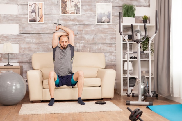 Homme en forme faisant des exercices de triceps avec haltère pendant la pandémie mondiale.