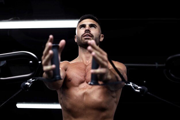 L'homme En Forme Et Musclé Entraîne Les Muscles Pectoraux Sur Un Simulateur De Bloc Dans La Salle De Gym.