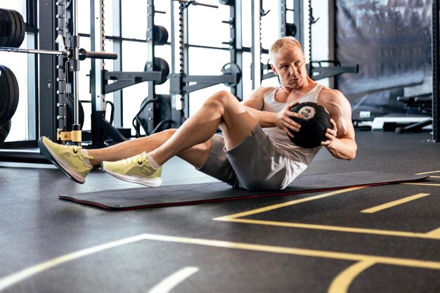 Homme en forme et musclé exerçant avec médecine-ball au gymnase