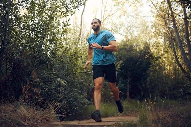 Homme en forme nature courir dans la forêt et courir pour la santé cardiovasculaire ou le bien-être du corps devant les arbres verts Coureur sportif entraînement de fitness cardio et s'entraîner à faire de l'exercice d'entraînement marathon tout-terrain