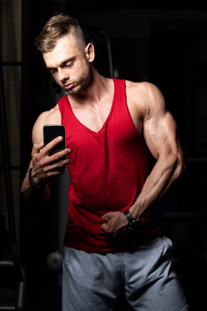 Homme en forme prenant selfie et posant des biceps