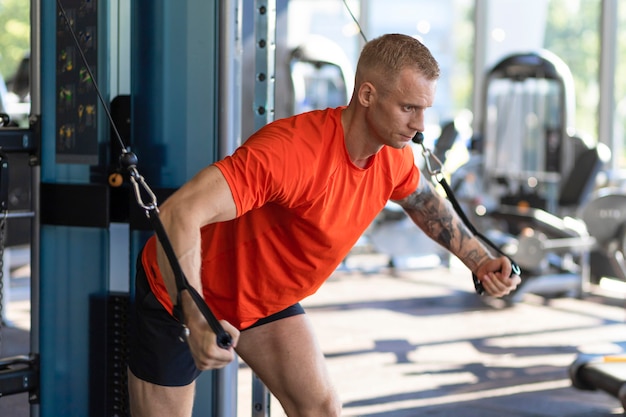 Homme fort d'athlète pompant des muscles dans le simulateur dans le gymnase. séance d'entraînement musculaire. musculation, sport, fitness.