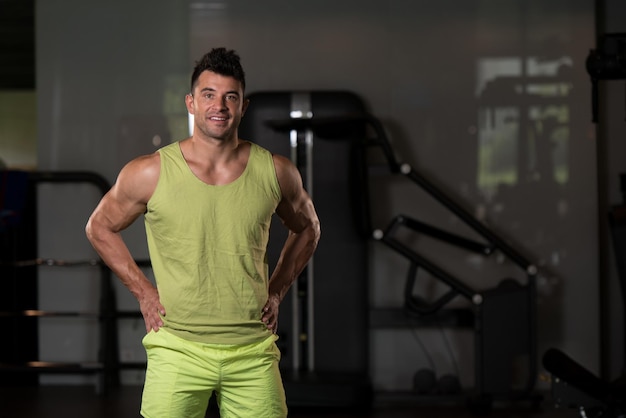 Homme fort dans la salle de gym de fond de t-shirt vert