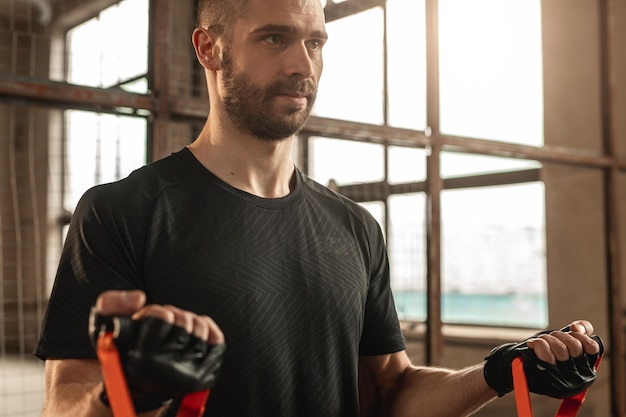 Homme fort exerçant avec des sangles de résistance